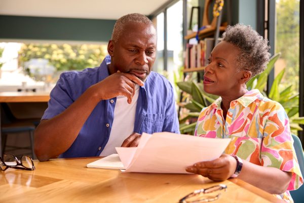 Senior Couple Sitting Around Table At Home Reviewing Finances